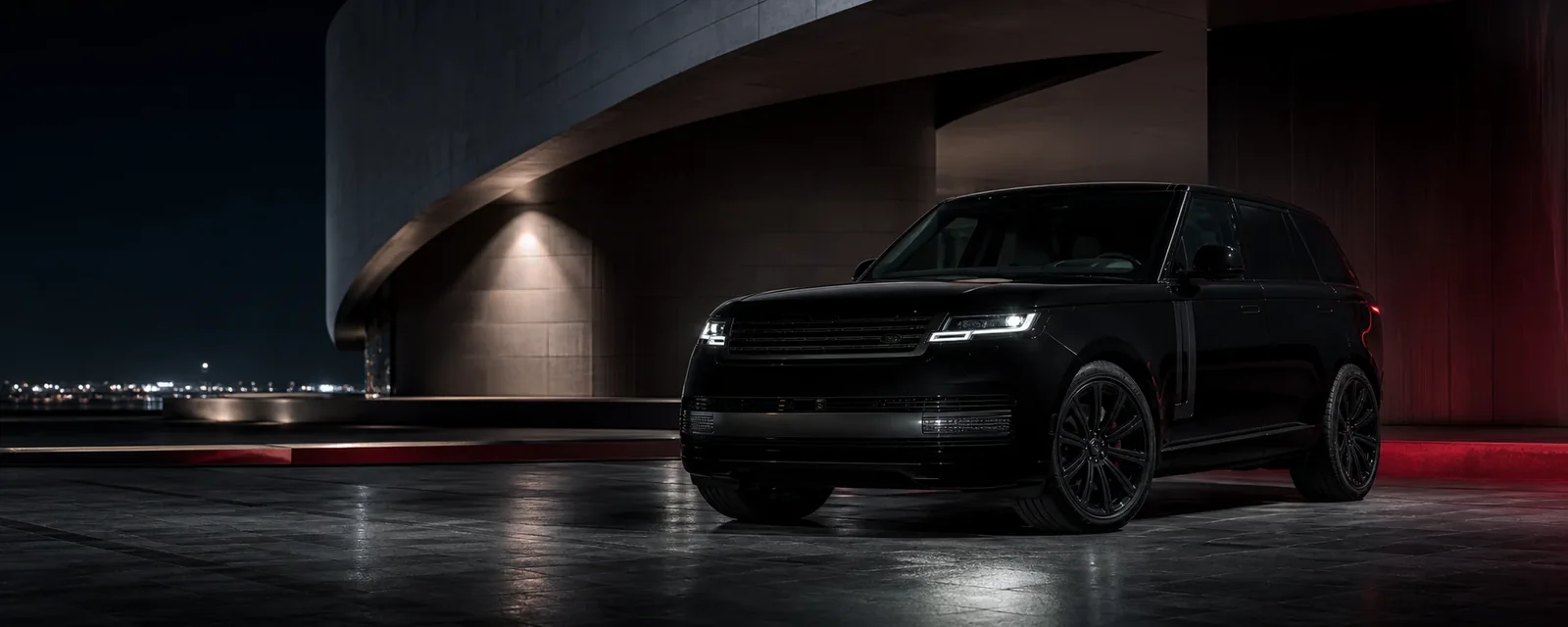 Black Range Rover outside illuminated architecture at night